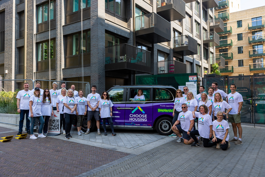 A group image of volunteers beside a wrapped purple cab for charity abseil